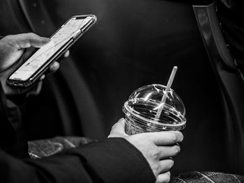 Cropped hands of person using mobile phone while holding drink