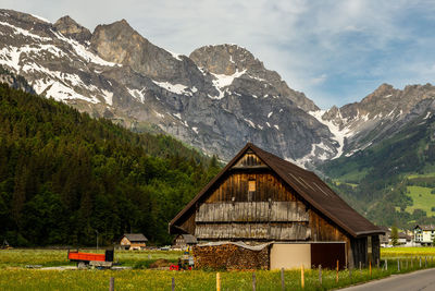 Built structure on field by mountain against sky