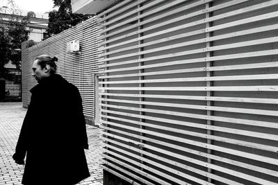 Rear view of man walking by pattern wall