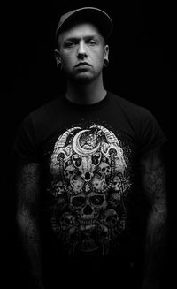 Portrait of young man standing against black background