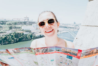 Portrait of young woman wearing sunglasses while standing against sky