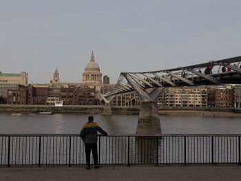 Rear view of man standing on bridge over river