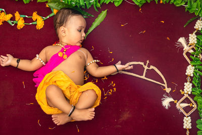 Cute indian boy dresses as lord rama with bow and flowers from top angle