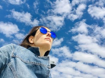 Low angle view of young woman looking away against sky