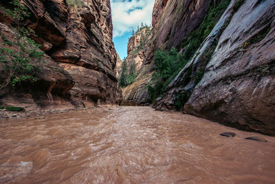 Scenic view of river flowing amidst rock formations against sky