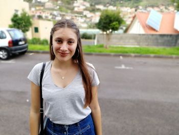 Portrait of smiling young woman standing on road