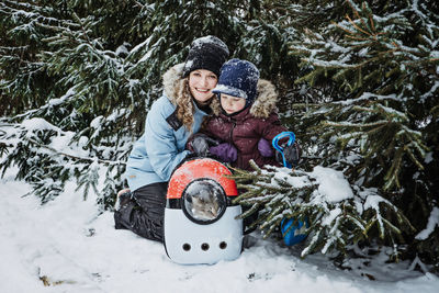 Portrait of happy family mother, son and cat in snowy winter park. outdoors portrait of mom and kid