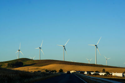 Wind turbines on field against clear blue sky