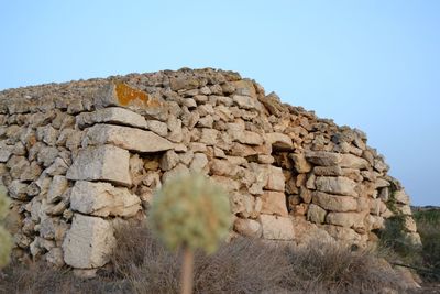 Low angle view of stone wall against clear blue sky