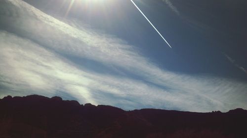 Low angle view of silhouette vapor trail in sky