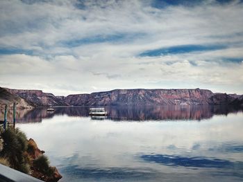 Scenic view of lake by rock formations against cloudy sky