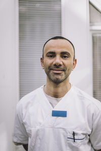 Portrait of smiling mature male doctor wearing lab coat at hospital