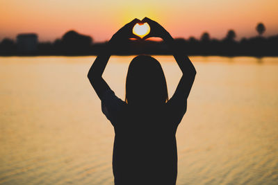 Silhouette woman standing at beach during sunset