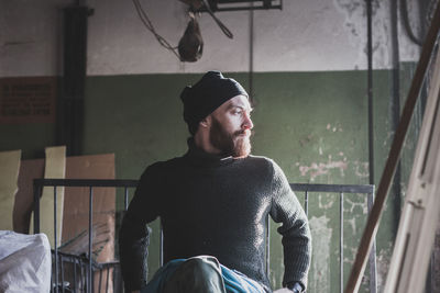 Man looking away while sitting on window