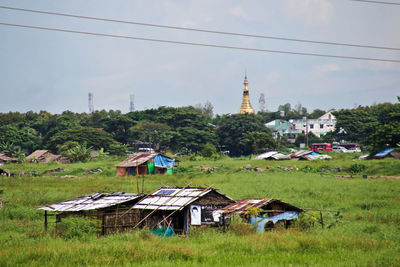 Houses and trees on field against sky