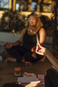 Hand of woman holding burning sandalwood at retreat center