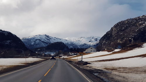 Road amidst snowcapped mountains against sky