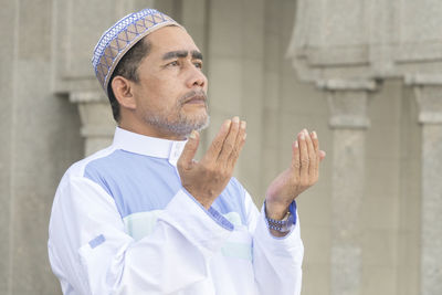 Close-up of man praying while standing at mosque