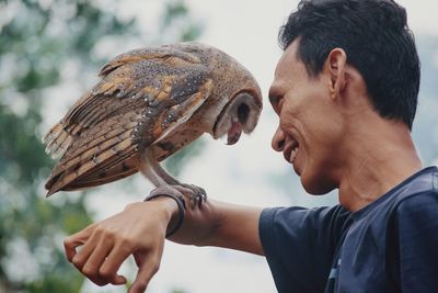 Smiling man holding owl on hand