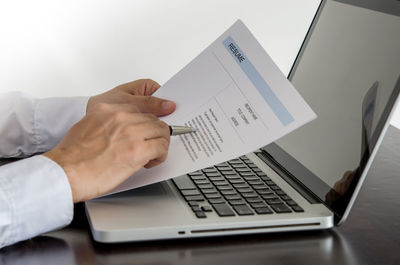 Cropped hands of businessman signing document at desk