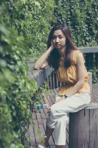 Portrait of young woman against plants