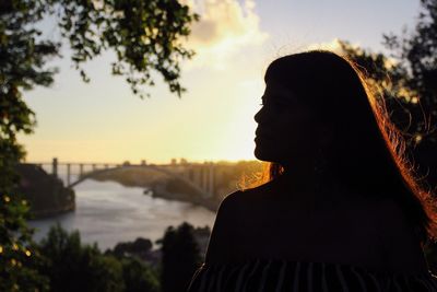 Close-up of silhouette woman standing against river at sunset