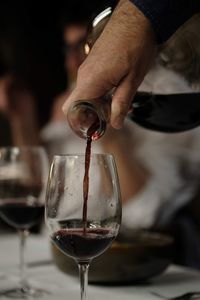 Close-up of hand pouring wine in glass