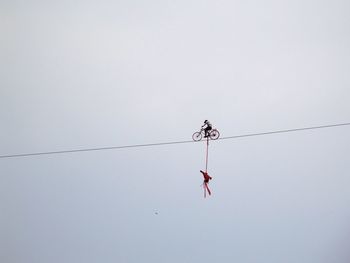 Low angle view of man riding bicycle against sky on rope