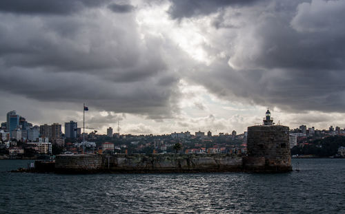 Sea by buildings against sky in city