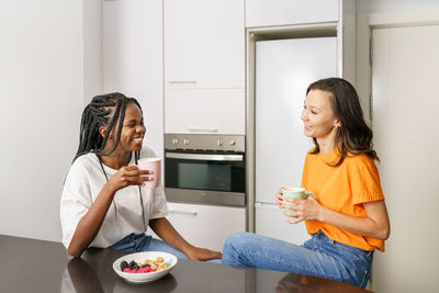 Friends talking while having breakfast at home