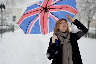 Woman with umbrella standing in snow