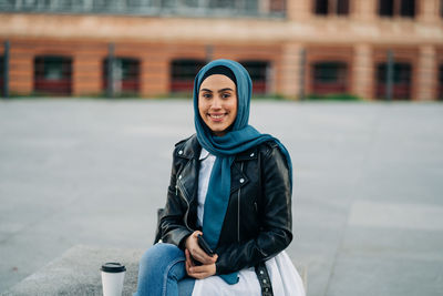 Portrait of smiling young woman sitting outdoors
