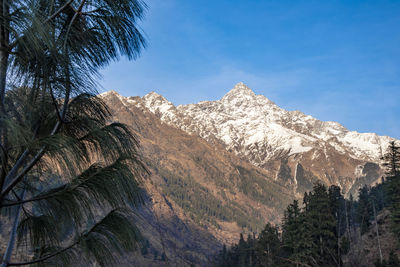 Low angle view of snowcapped mountains against blue sky