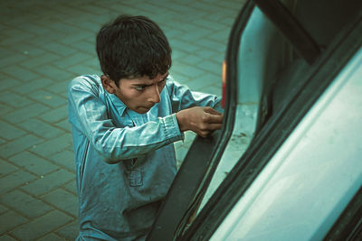 Boy repairing car outdoors