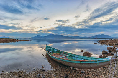 Boat moored on beach against sky