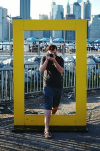 Man photographing while standing on yellow rectangle