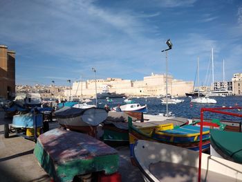 Boats moored at harbor in city against sky