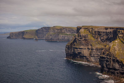 Scenic view of sea and cliff against sky