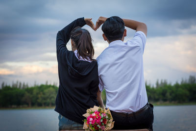 Rear view of couple kissing against sky