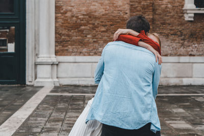 Rear view of couple walking against building