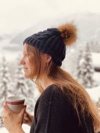 Woman with coffee cup against snow covered land