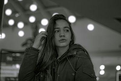 Portrait of young woman standing against illuminated lights