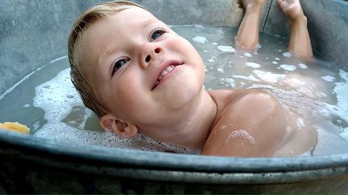 Smiling boy in the bathtub with foam