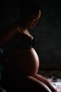 Side view of pregnant woman sitting at home