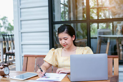 Young woman using phone while sitting on table