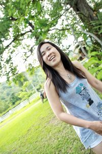 Young woman smiling while standing against trees