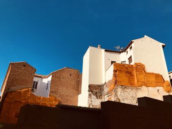 Orange in blue - low angle view of buildings against blue sky