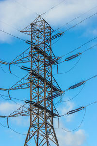 Low angle view of electricity pylon against blue sky