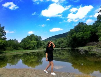 Full length of woman standing by lake against sky