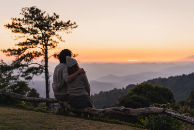 Rear view of woman standing on mountain against sky during sunset